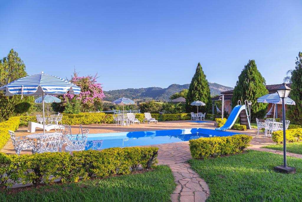 a pool with a slide and chairs and umbrellas at Pousada Lua Luana in Cambuquira