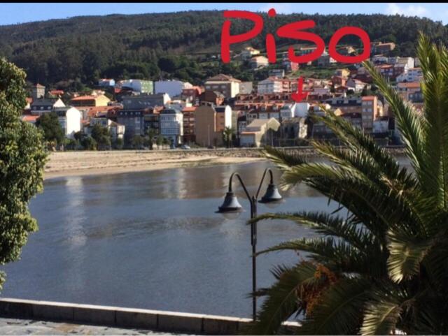 a sign that reads paso and a river with a city at Apartamento junto al paseo marítimo de Cee in Cee