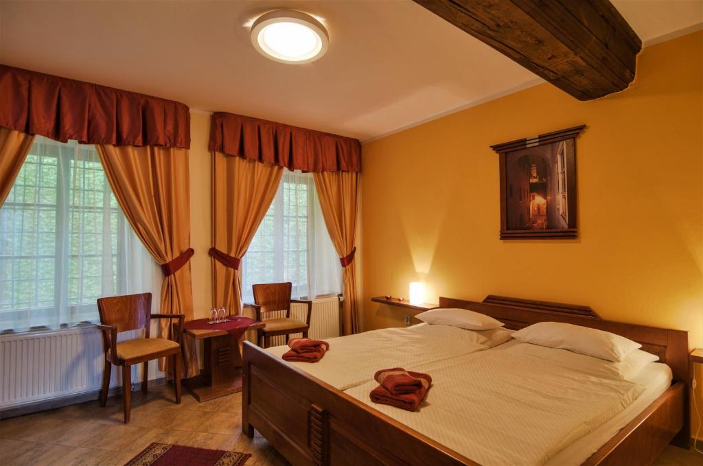 a bedroom with a large bed and chairs and windows at Pension Pod Radnicí in Český Krumlov