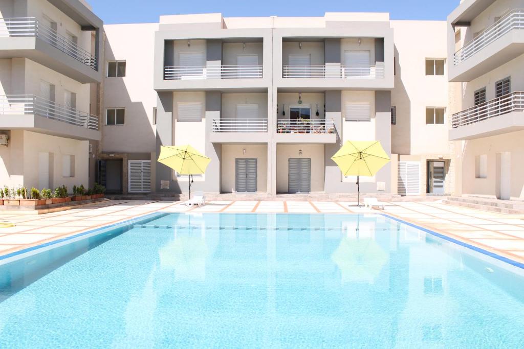 een zwembad voor een gebouw met parasols bij Azra Homes Famille uniquement in Saidia 