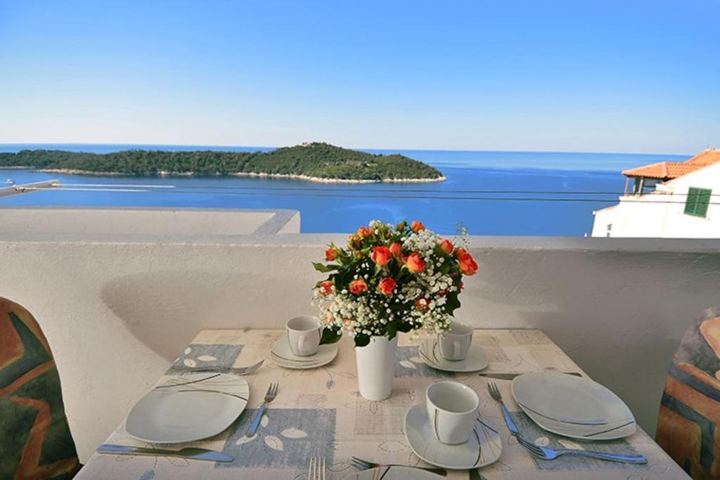 a table with a vase of flowers on the beach at Dubrovnik Apartment Vista Mar in Dubrovnik