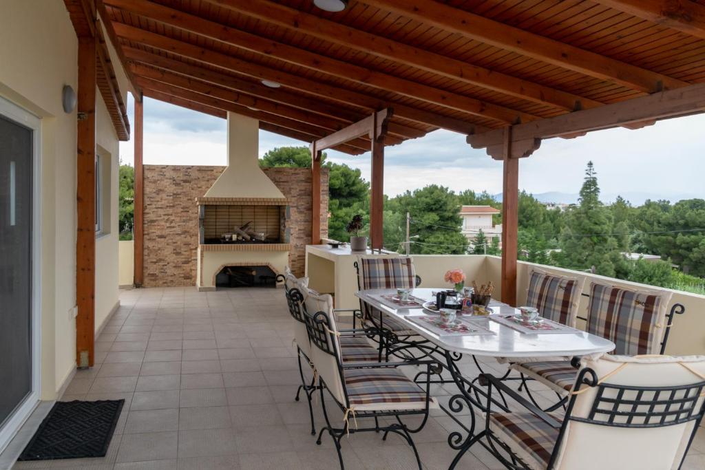 a patio with a table and chairs and a fireplace at Rose's House (Near Airport) in Artemida