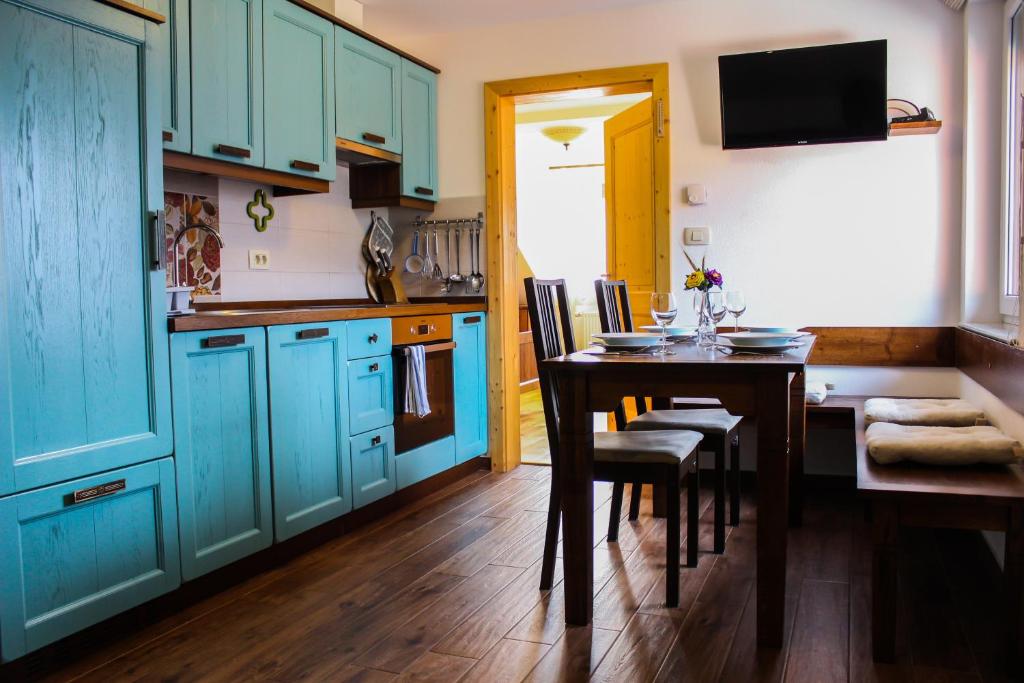 a kitchen with blue cabinets and a table with chairs at Kmetija Na Čendavš in Cerkno