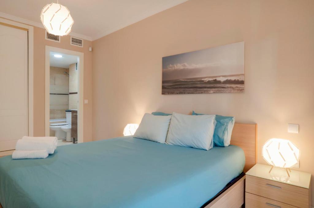 um quarto com uma cama com lençóis azuis e duas luzes em Beach and golf apartament em Benalmádena