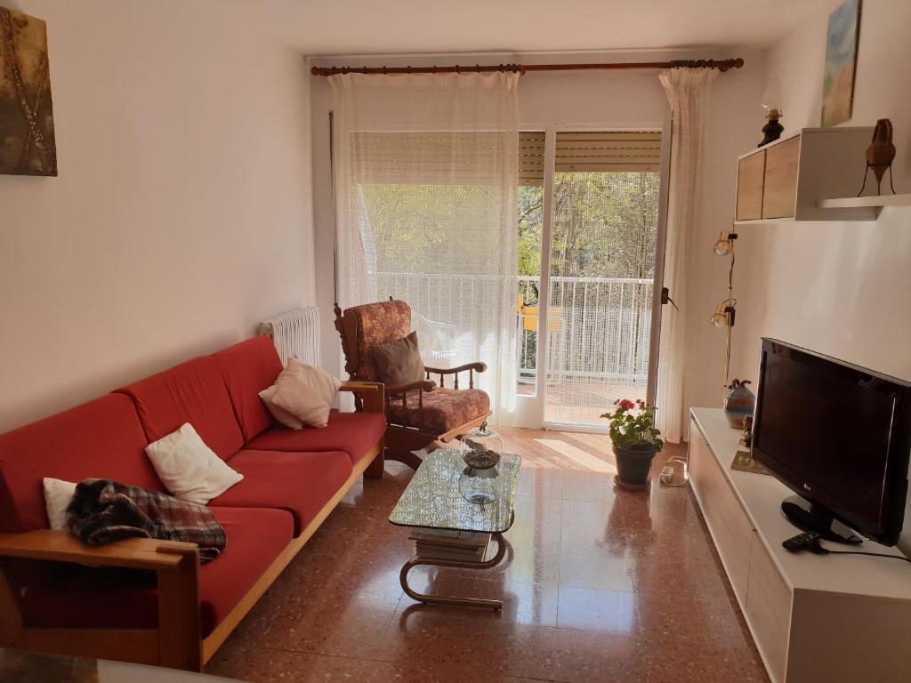 sala de estar con sofá rojo y TV en Ca la Rita, en Castellfollit de la Roca