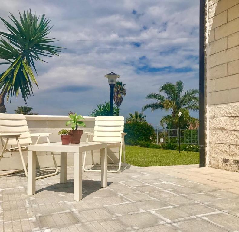 a patio with a table and chairs and a palm tree at Casa Brucoli in Brucoli