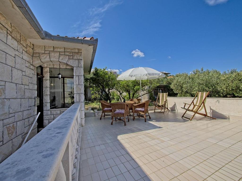 a patio with a table and chairs and an umbrella at Apartman Nikica in Postira