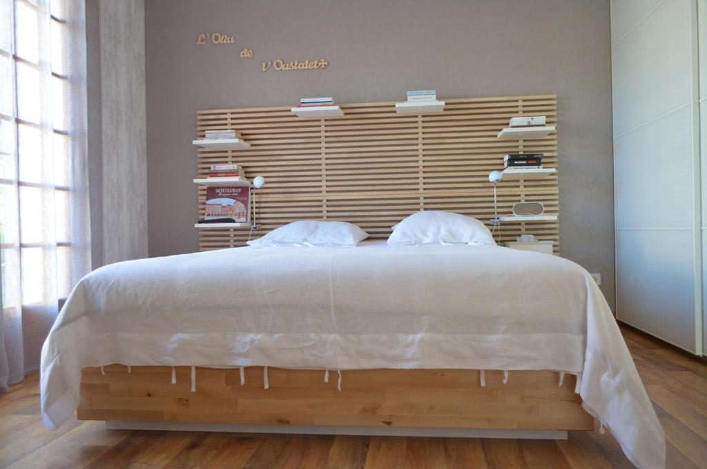 Schlafzimmer mit einem großen weißen Bett mit einem Kopfteil aus Holz in der Unterkunft L'OLIU DE L'OUSTALET in Castelsarrasin