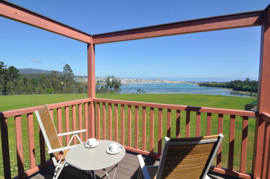 een balkon met een tafel en 2 stoelen en uitzicht op het water bij Cabanas Da Barcela in Barreiros