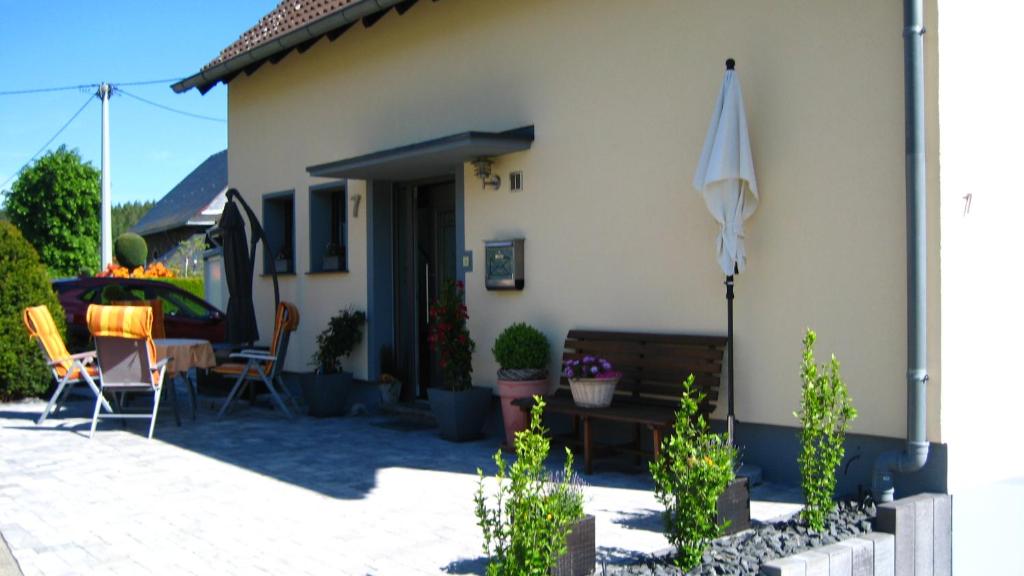 a house with a patio with an umbrella and chairs at Gästezimmer Waldblick in Wimbach