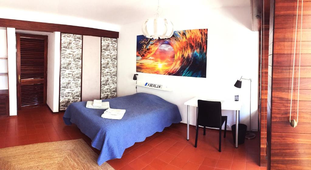 um quarto com uma cama, uma mesa e um quadro em Carcavelos Beach Studio em Lombos