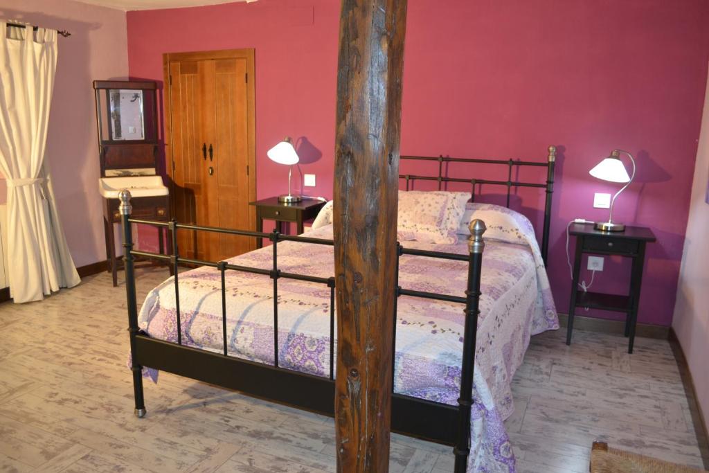 a bedroom with a bed and a pink wall at El Pajar de la Abuela in Arcas