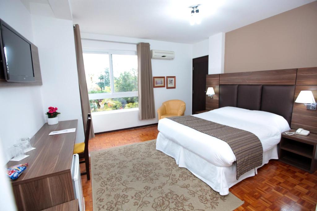 een hotelkamer met een bed en een televisie bij Hotel Obino Bagé in Bagé