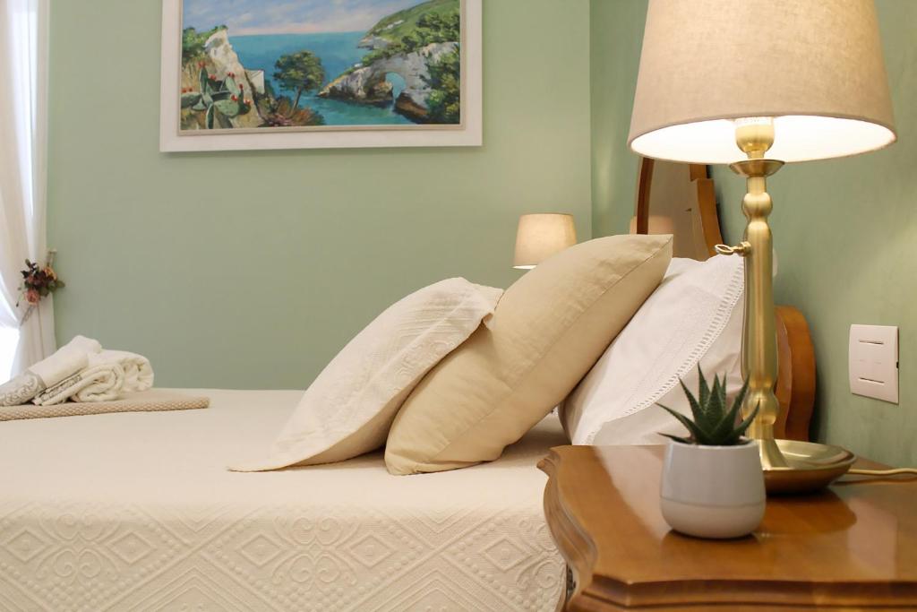 a bed with white pillows and a table with a lamp at Estlevante B&B in Vieste
