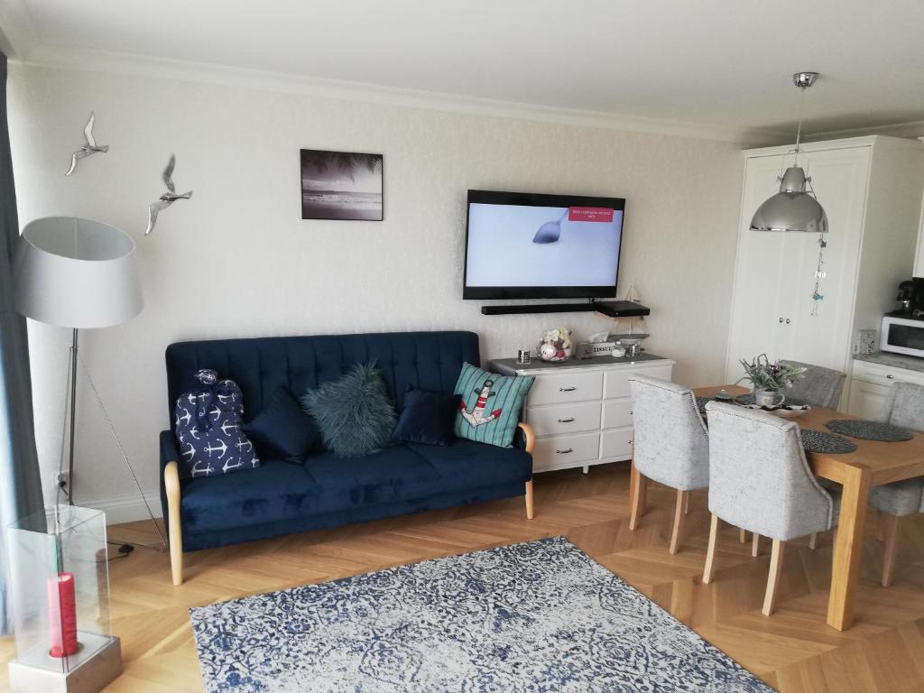 a living room with a blue couch and a table at Apartament na Morskim Wzgórzu in Mechelinki