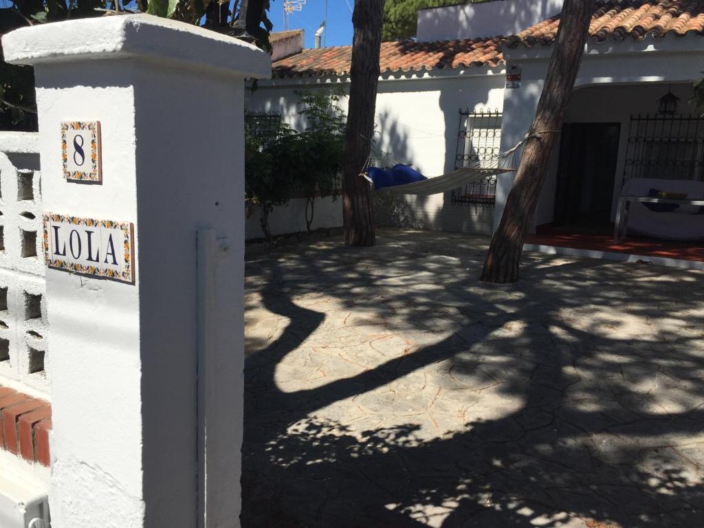 a white fence with a sign that says lola in front of a house at Chalet adosado playa de La Barrosa in Chiclana de la Frontera