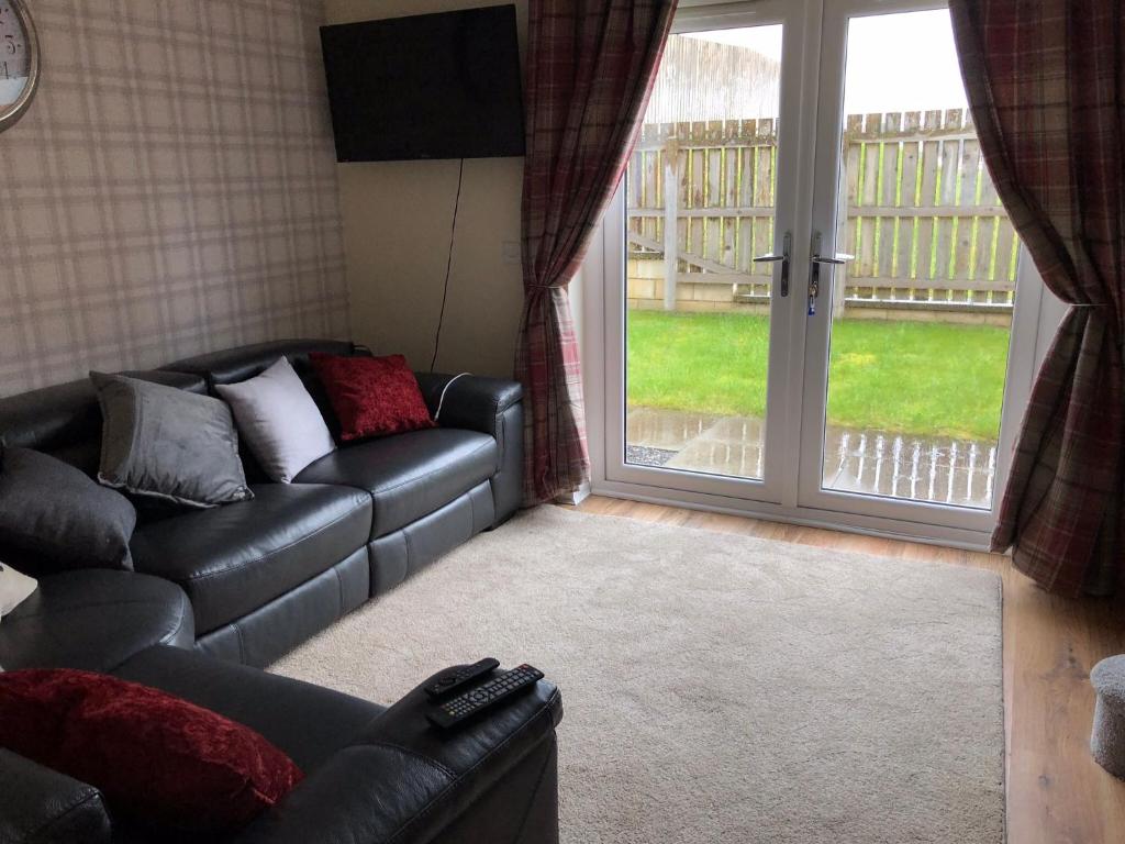 - un salon avec un canapé et une porte coulissante en verre dans l'établissement 41 Larchwood Drive Holiday Home, à Inverness