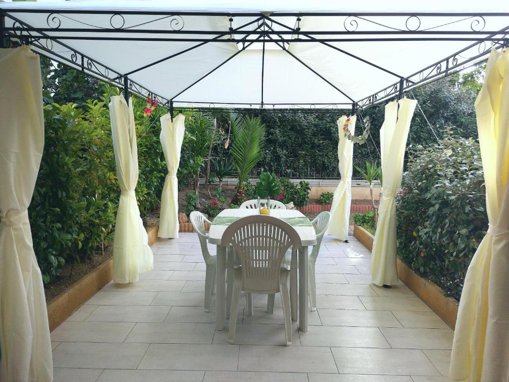 eine Terrasse mit einem Tisch, Stühlen und einem Sonnenschirm in der Unterkunft ValeValeHome - home gallery with fully equipped kitchen, reserved parking, big garden - IUN F3158 in Olbia