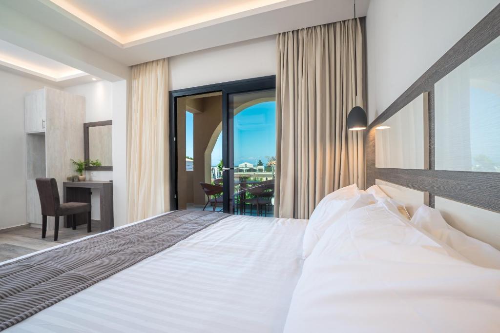 a bedroom with a large bed and a balcony at ABATON Luxury Resort in Tsilivi