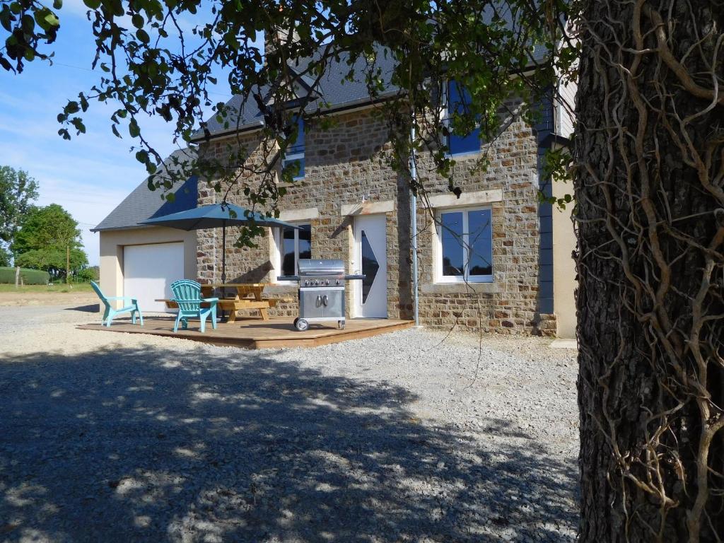 una casa in mattoni con due sedie e un grill di L'Abri-cottage a Isigny-le-Buat