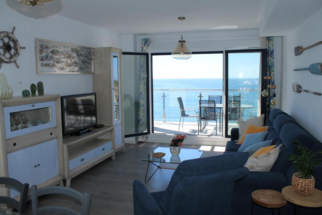 salon z niebieską kanapą i widokiem na ocean w obiekcie Dúplex playa Cabria w Almuñécar