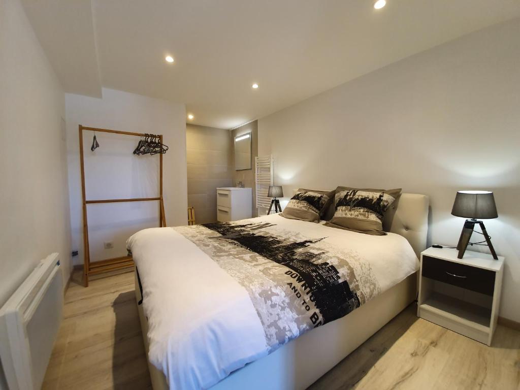 una camera da letto con un letto grande con lenzuola bianche di Appartement T2 proche gare et centre Bourgoin a Bourgoin