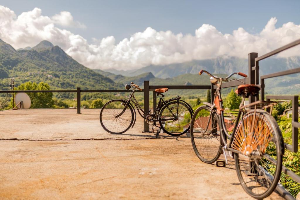 un vélo garé à côté d'une clôture avec des montagnes en arrière-plan dans l'établissement Guest House Luna, à Virpazar