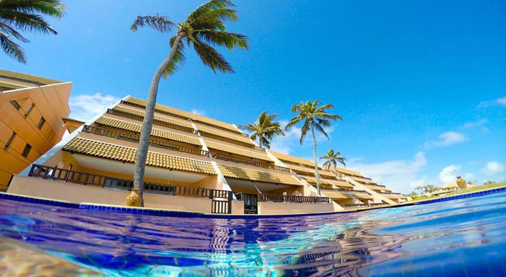 a hotel with a palm tree and a swimming pool at Cumbuco Ocean View in Cumbuco