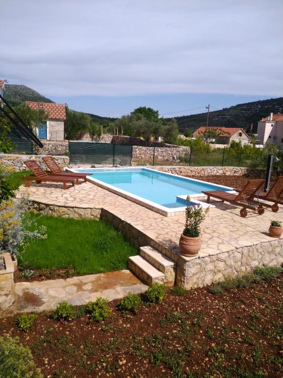 a swimming pool in a yard with chairs at Kuca za odmor Bozena in Vrsine