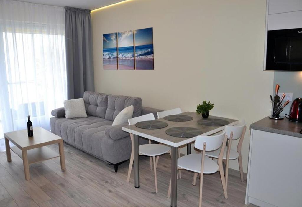 a living room with a couch and a table and chairs at Apartament Srebrny z garażem in Kołobrzeg