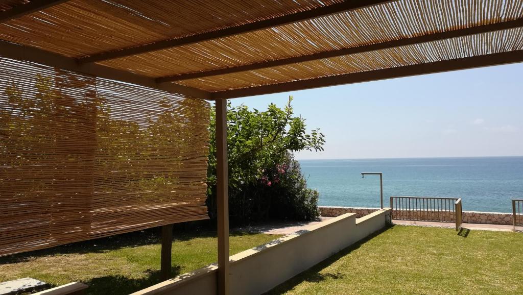 a view of the ocean from a wooden pergola at Dip In The Blue - 1 in Agios Georgios