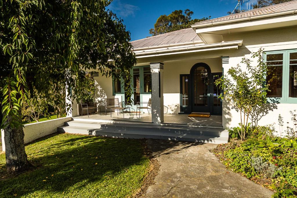 a white house with a porch and a tree at Deco Villa in Havelock North