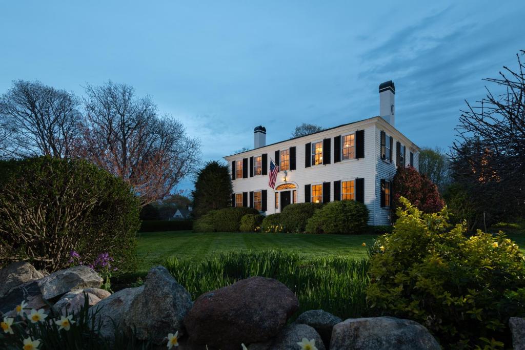 una grande casa bianca con rocce nel cortile di Candleberry Inn on Cape Cod a Brewster