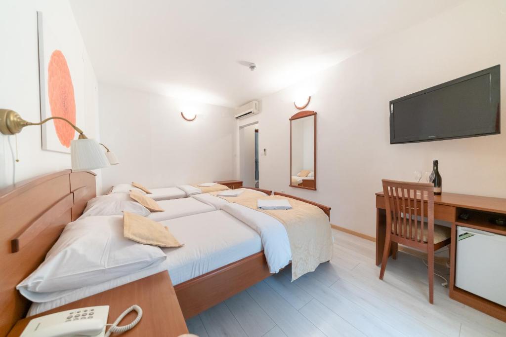 a bedroom with a bed and a desk and a television at Hotel Hygge in Biograd na Moru