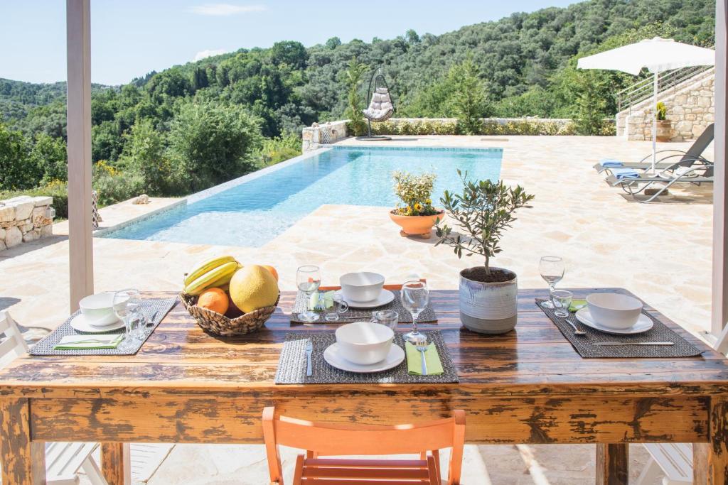 a wooden table with food on it next to a pool at Villa Venetia Corfu in Agnítsini