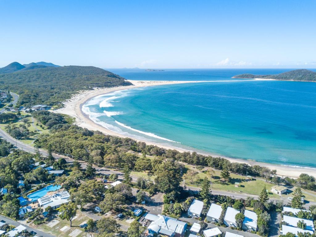 an aerial view of a beach and the ocean at Fingal Bay Holiday Park in Fingal Bay