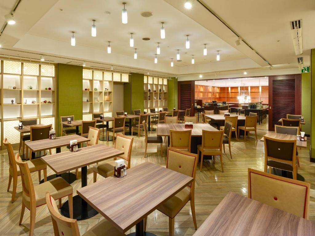 a restaurant with wooden tables and chairs at Mitsui Garden Hotel Kumamoto in Kumamoto