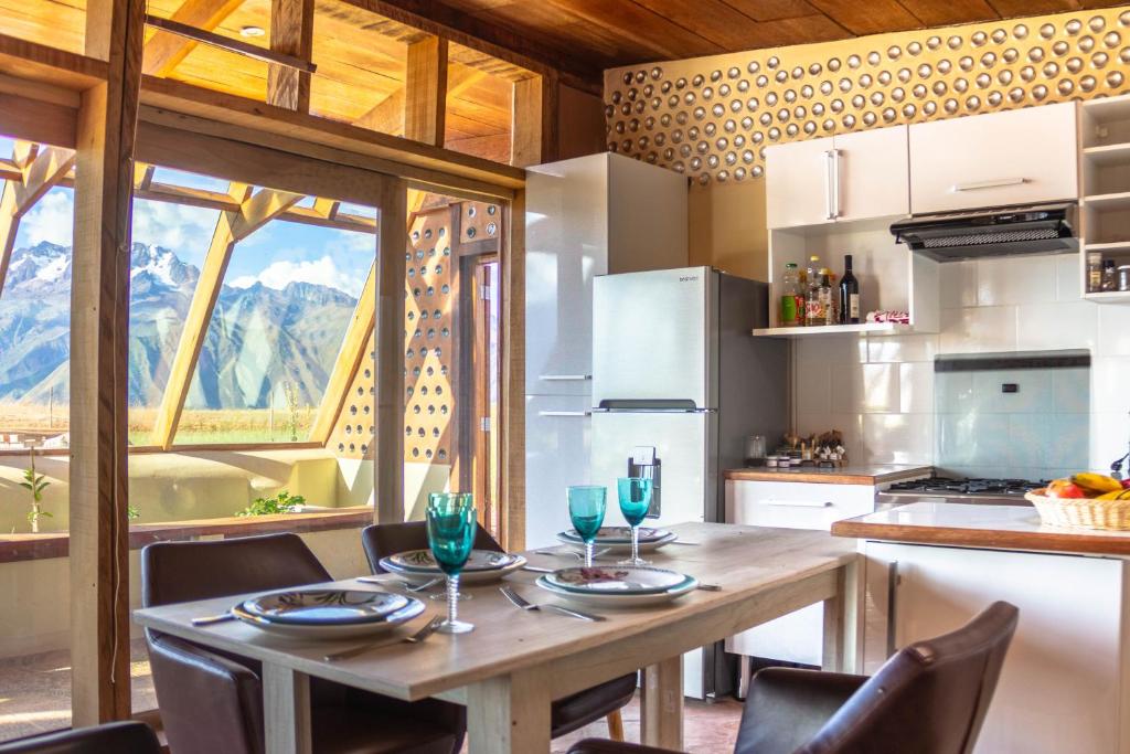 cocina con mesa de madera con sillas y comedor en Casa 100% ecológica con vista a los glaciares andinos en Maras