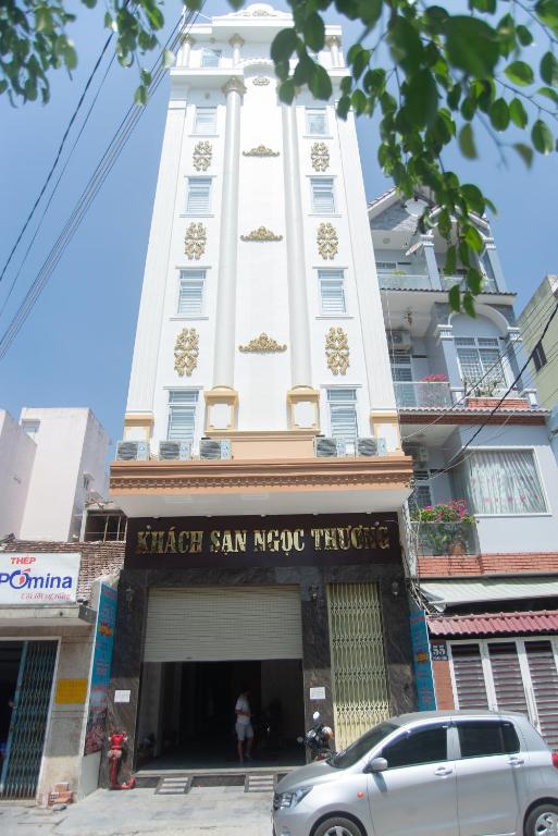 a tall white building with a car parked in front of it at Khách sạn Ngọc Thương in Quy Nhon