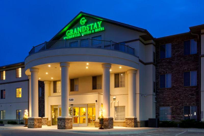 un edificio con una señal verde encima en GrandStay Residential Suites Hotel Faribault, en Faribault