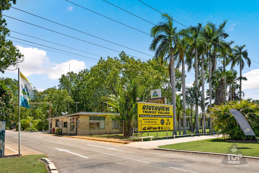 un letrero amarillo al lado de una carretera con palmeras en Riverview Tourist Village, en Katherine