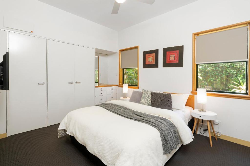 a white bedroom with a large bed and two windows at Byron Getaway @the Crest in Byron Bay
