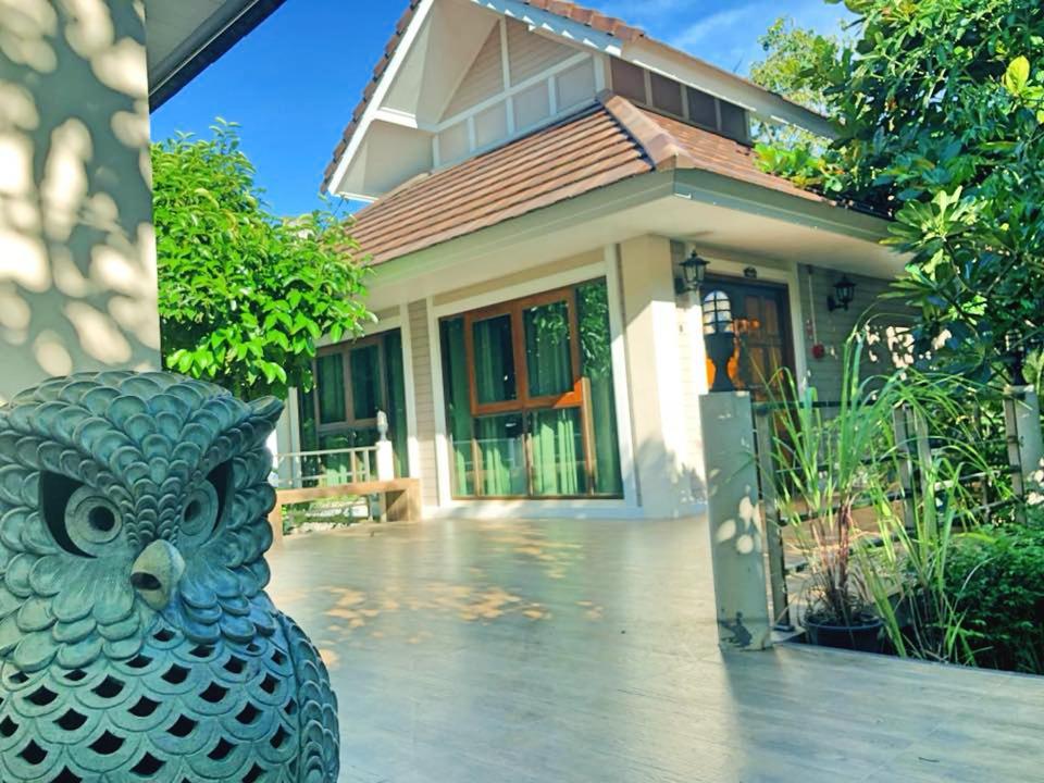 Damnoen Care Resort في دامنون سادواك: منزل أمامه تمثال بوم