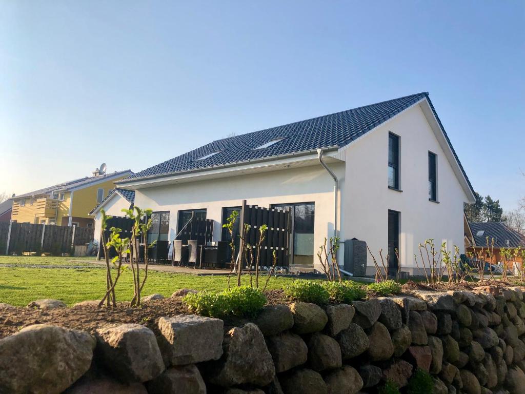 a white house with a black roof and a stone wall at Ferienhaus Traumspot in Wiek auf Rügen 