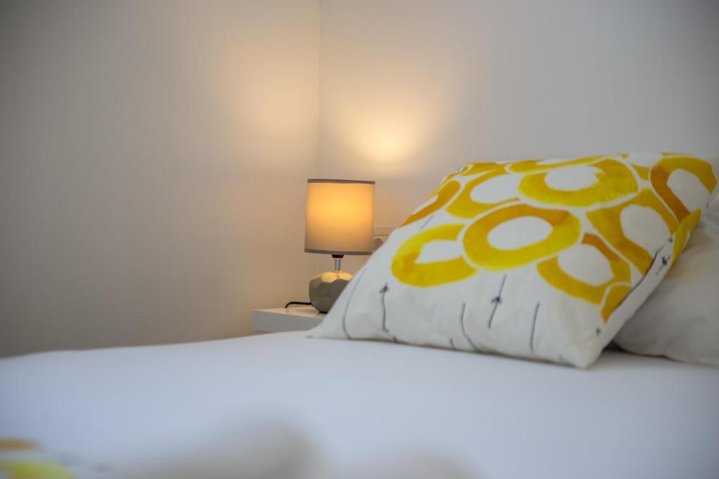 uma cama com uma almofada amarela e branca e um candeeiro em Apartman More em Selce
