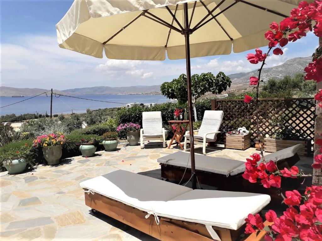 - une terrasse avec 2 chaises et un parasol dans l'établissement Hand Crafted with sea View, à Karistos