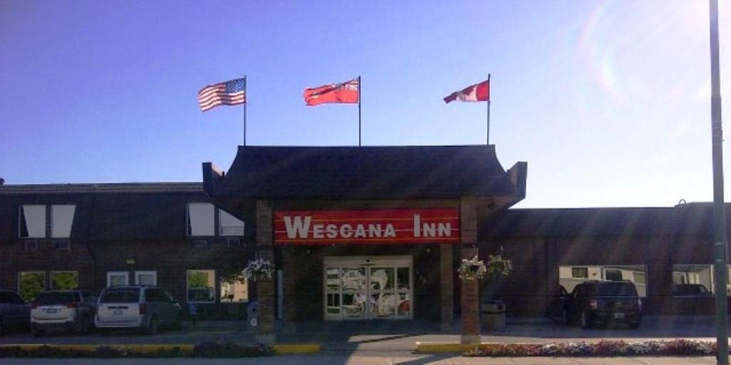 tres banderas canadienses en la parte superior de una tienda en Wescana Inn, en The Pas