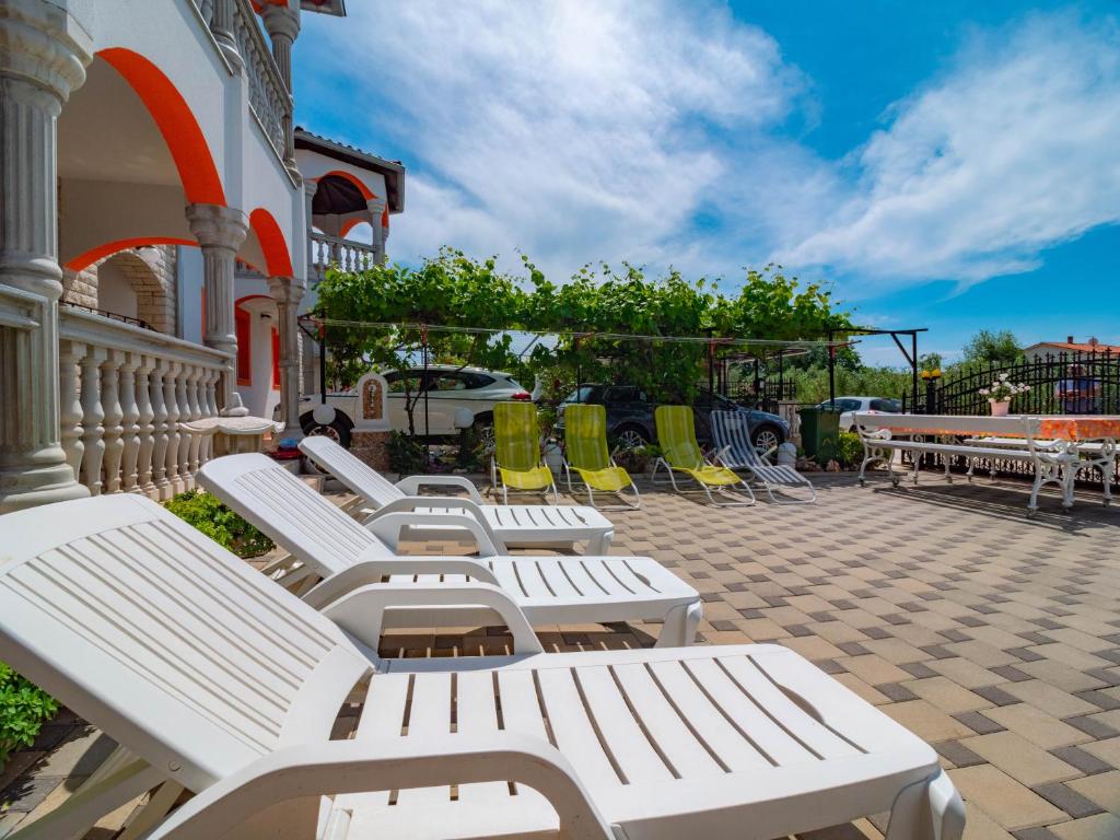 a row of white benches sitting on a patio at Apartments Anamarija in Medulin