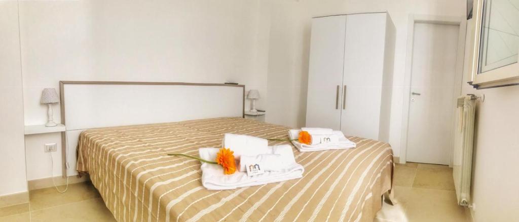 Cette chambre d'hôtel comprend un lit avec des serviettes et des fleurs. dans l'établissement PETRAMARE, à Cursi