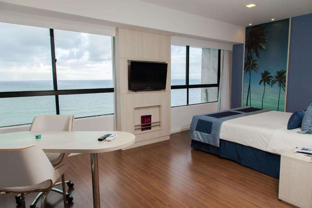 Mercure Recife Navegantes في ريسيفي: غرفة نوم بسرير ومدفأة وتلفزيون